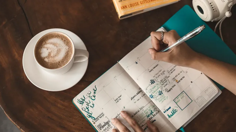 Person completing a symptom and menstrual cycle tracking diary at a kitchen table
