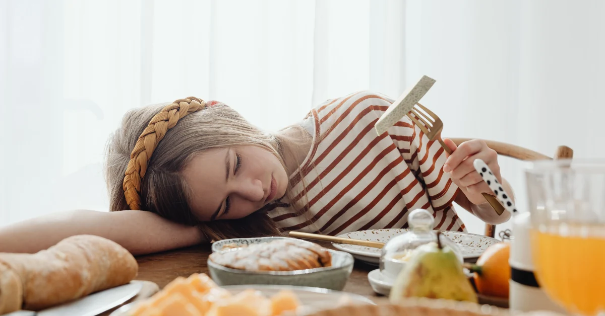 Person at a kitchen table, tired, pushing away a plate with bread