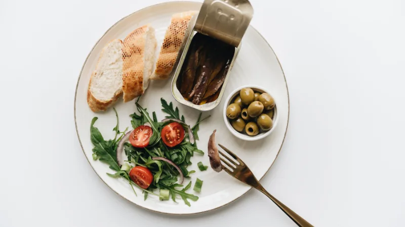 Mediterranean-style plate with vegetables, olive oil, and fish on a kitchen counter