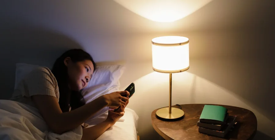 Phone showing a simple symptom-tracking app screen on a bedside table