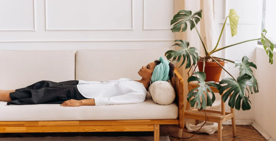 Person resting on a couch with a cool cloth on their forehead