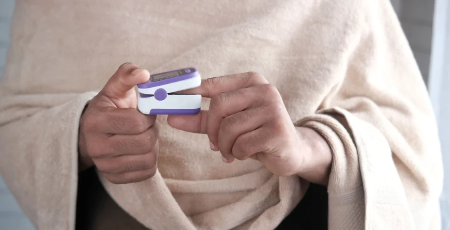 Pulse oximeter clipped on a fingertip, neutral home setting