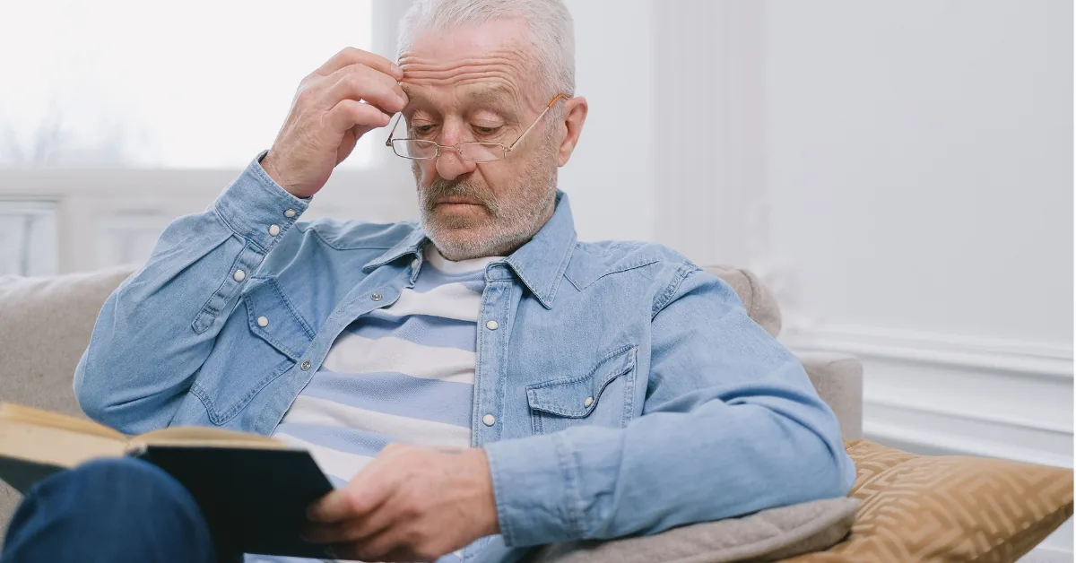 An older adult resting comfortably on a couch in a peaceful home setting with soft natural daylight.