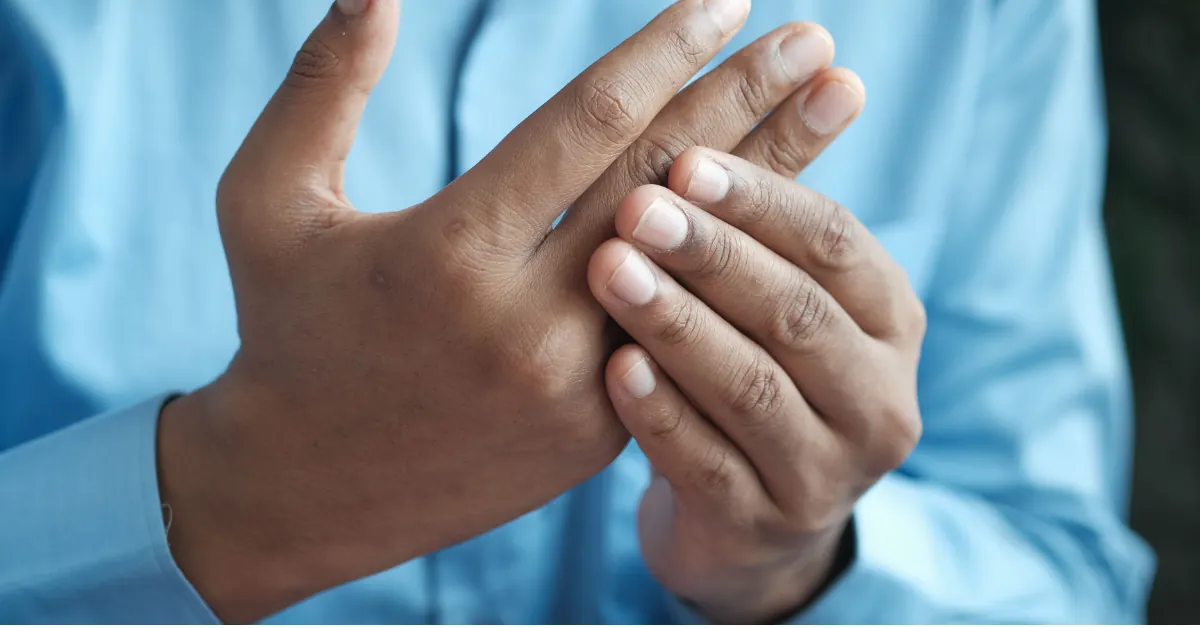 A person rubbing their hand or wrist while resting on a couch, calm afternoon light, dignified and not staged