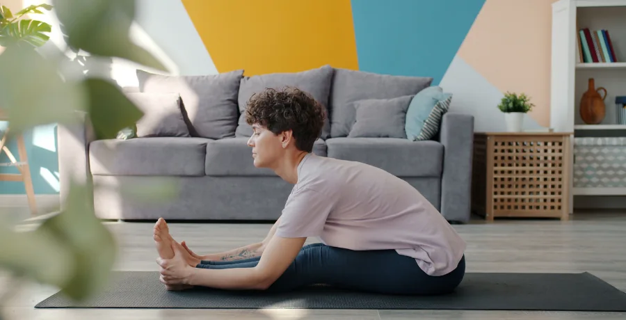 A person doing gentle yoga or stretching at home, calm and realistic, not overly staged