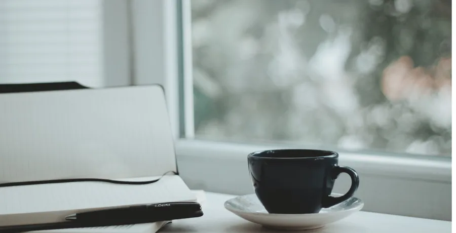 A simple daily symptom notebook next to a cup of tea for tracking symptoms between appointments
