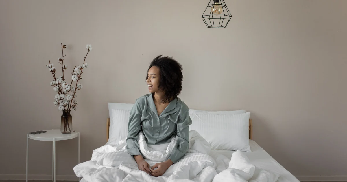 Young woman resting on bed with a hot water bottle on her abdomen for abdominal discomfort
