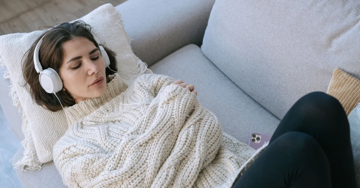 Person resting on a couch with a heating pad on the abdomen, representing fatigue associated with inflammatory bowel disease
