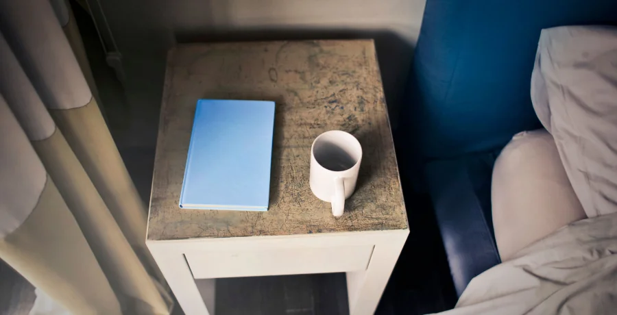 Bedside table at night, clock at 11:30, cold half-finished cup