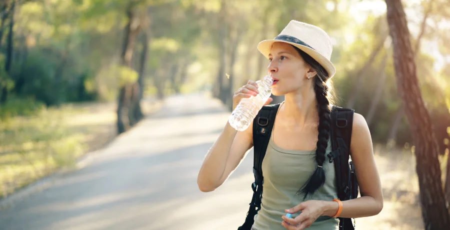Jogger or hiker on a shaded trail holding a refillable bottle