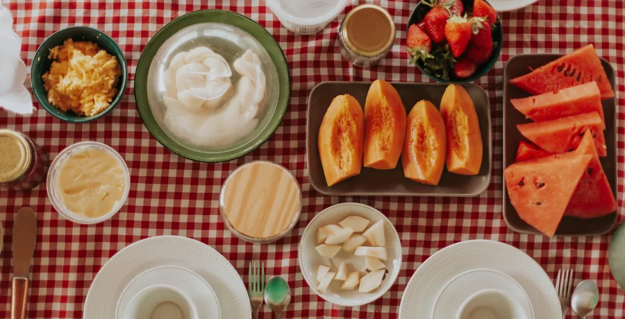 Flat-lay of water-rich foods: cucumber, watermelon, oranges, yogurt, soup