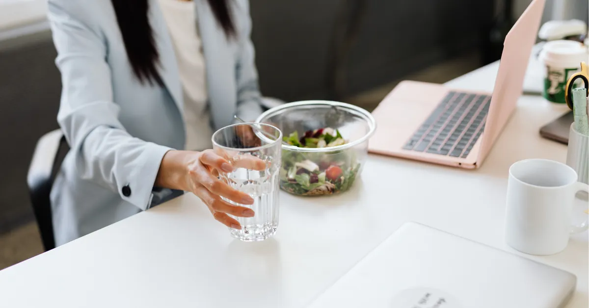 Person at a desk mid-afternoon with an empty water bottle beside a laptop