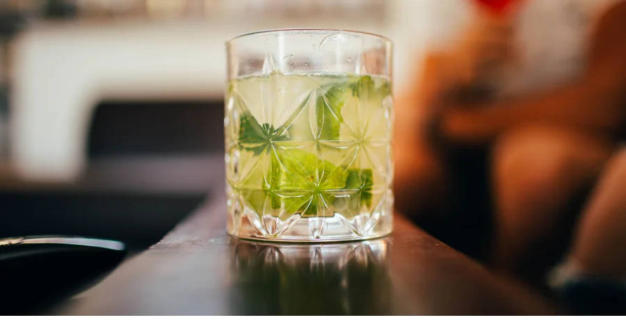 Sparkling water with lime at a social table, friends blurred behind