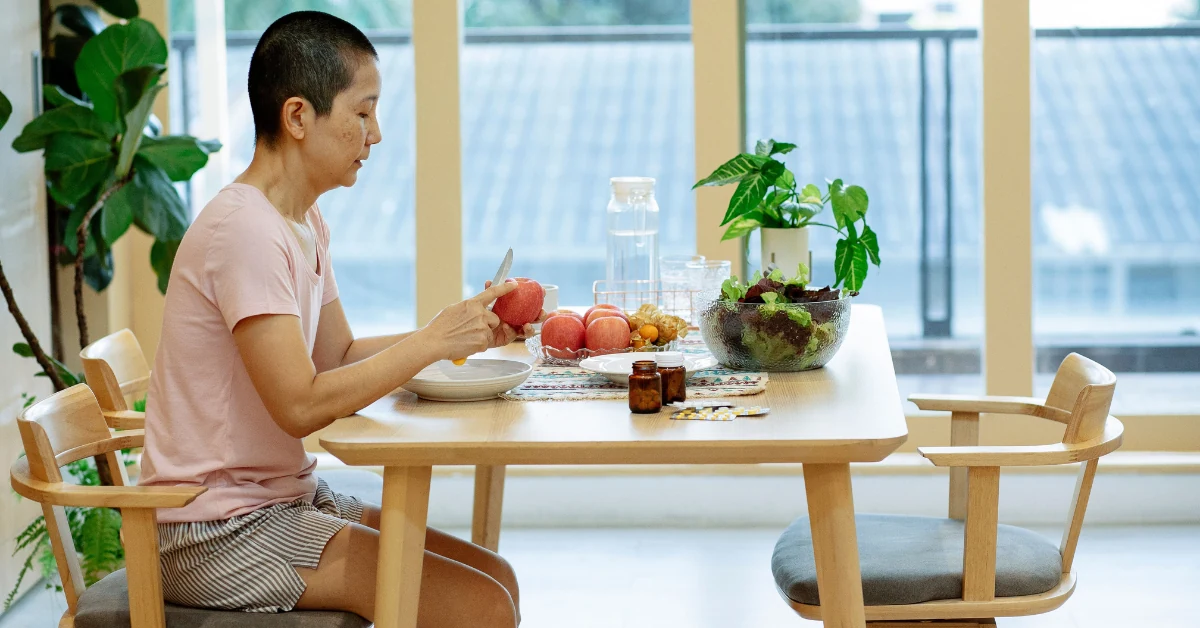 Adult reading a prescription bottle label while sitting at a kitchen table in morning light