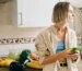 Person holding a glass of water at a kitchen counter in grey morning light