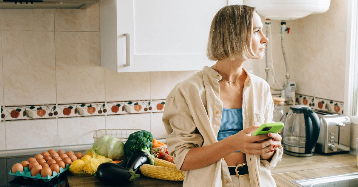 Person holding a glass of water at a kitchen counter in grey morning light