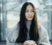 Person standing by a window on a grey winter morning holding a mug