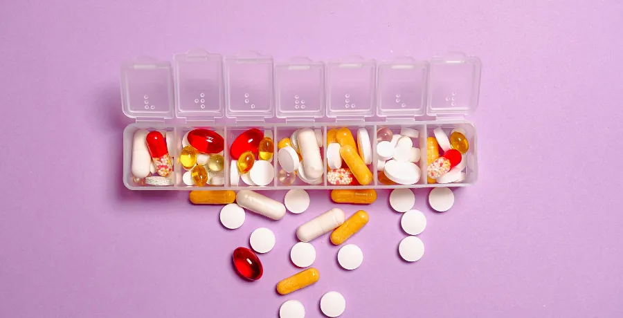 Weekly pill organizer beside a notebook energy log