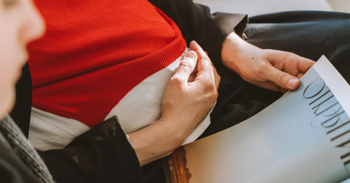 Pregnant woman resting on a sofa in soft daylight, hand on belly