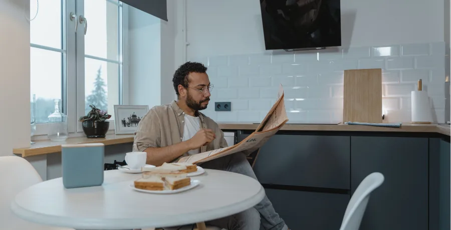 Light therapy box on a breakfast table, person eating and reading beside it